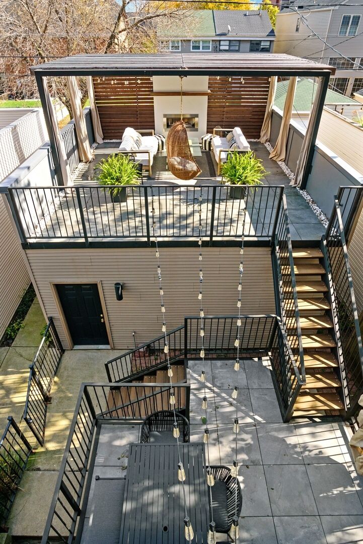 an aerial view of a house with stairs and patio furniture in the back yard area