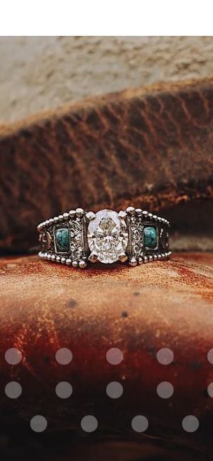 a diamond and emerald ring sitting on top of a piece of leather