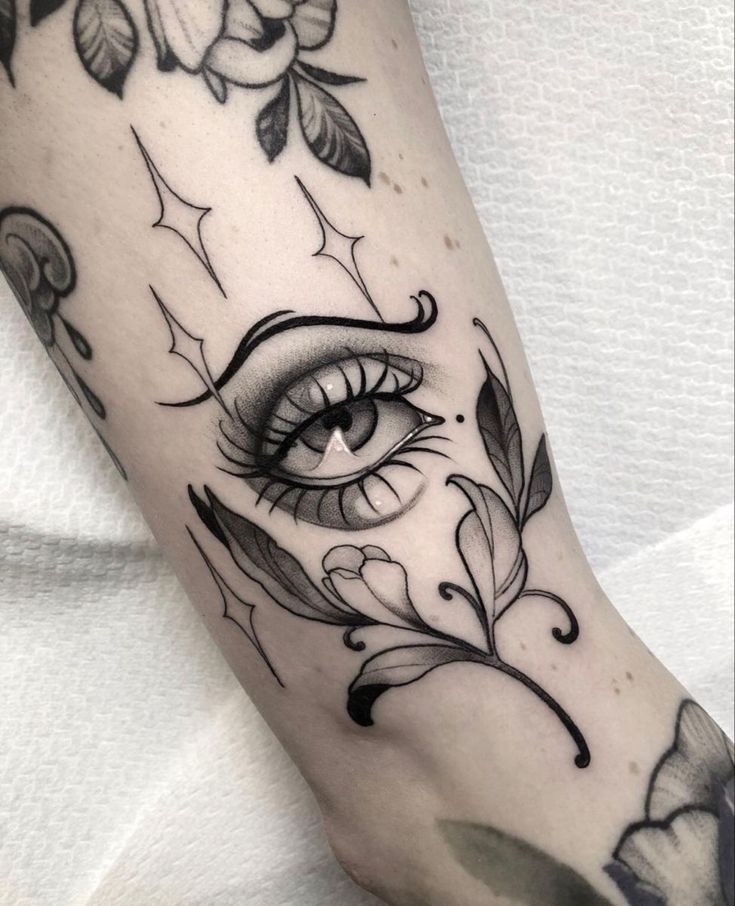 a woman's leg with an eye and flowers on the left side of her arm