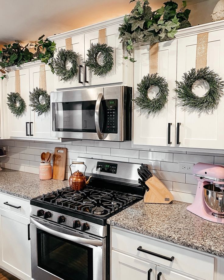 a kitchen decorated for christmas with wreaths hanging on the wall and stove top oven