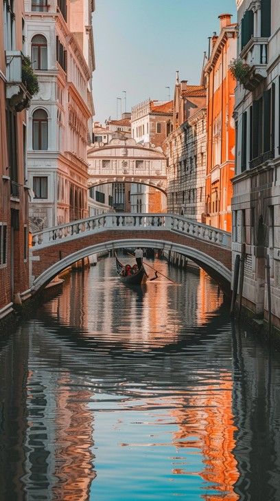 a gondola in the middle of a canal with buildings on both sides and a bridge above it