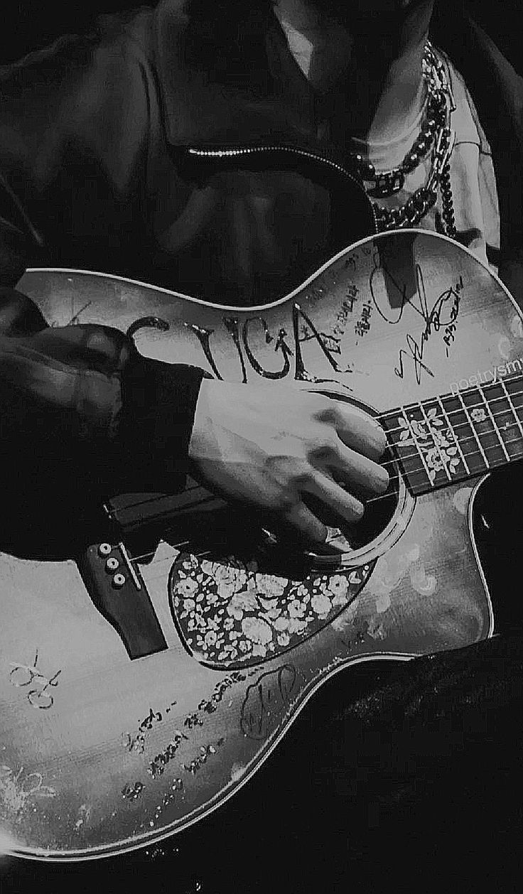 black and white photograph of a man playing an acoustic guitar with his name on it