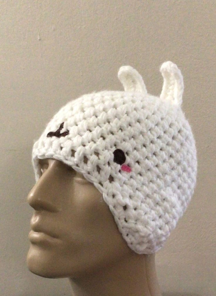 a white crocheted hat with an animal on the front and one pink nose