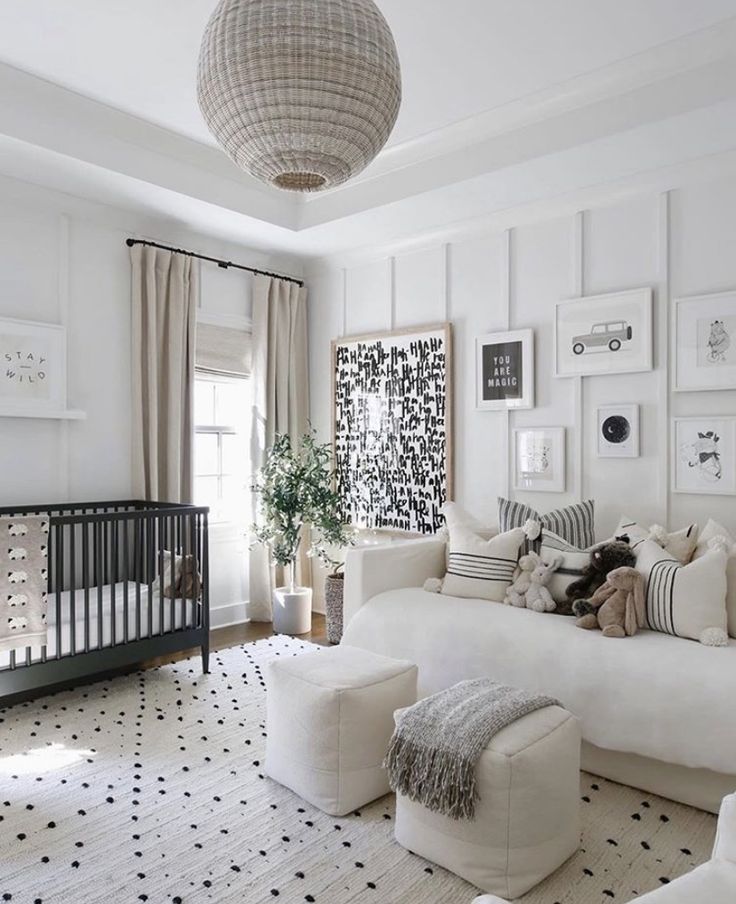 a living room with white furniture and black and white decor on the walls, along with a baby's crib