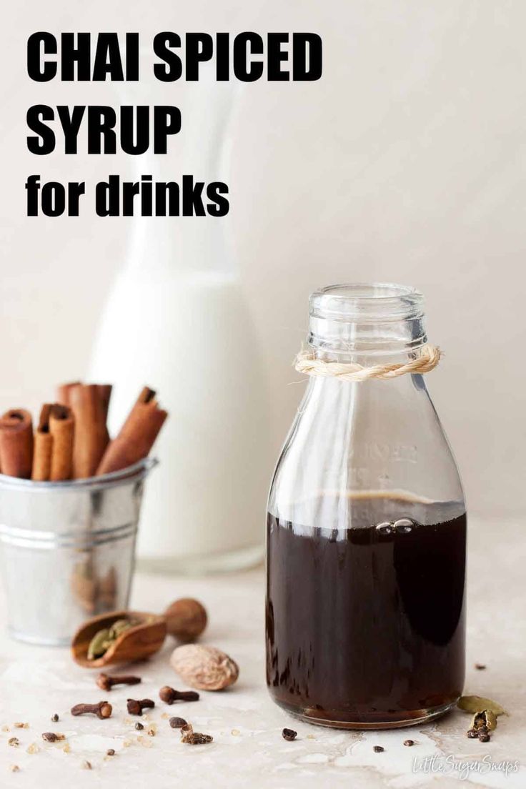 a glass bottle filled with syrup next to some cinnamons