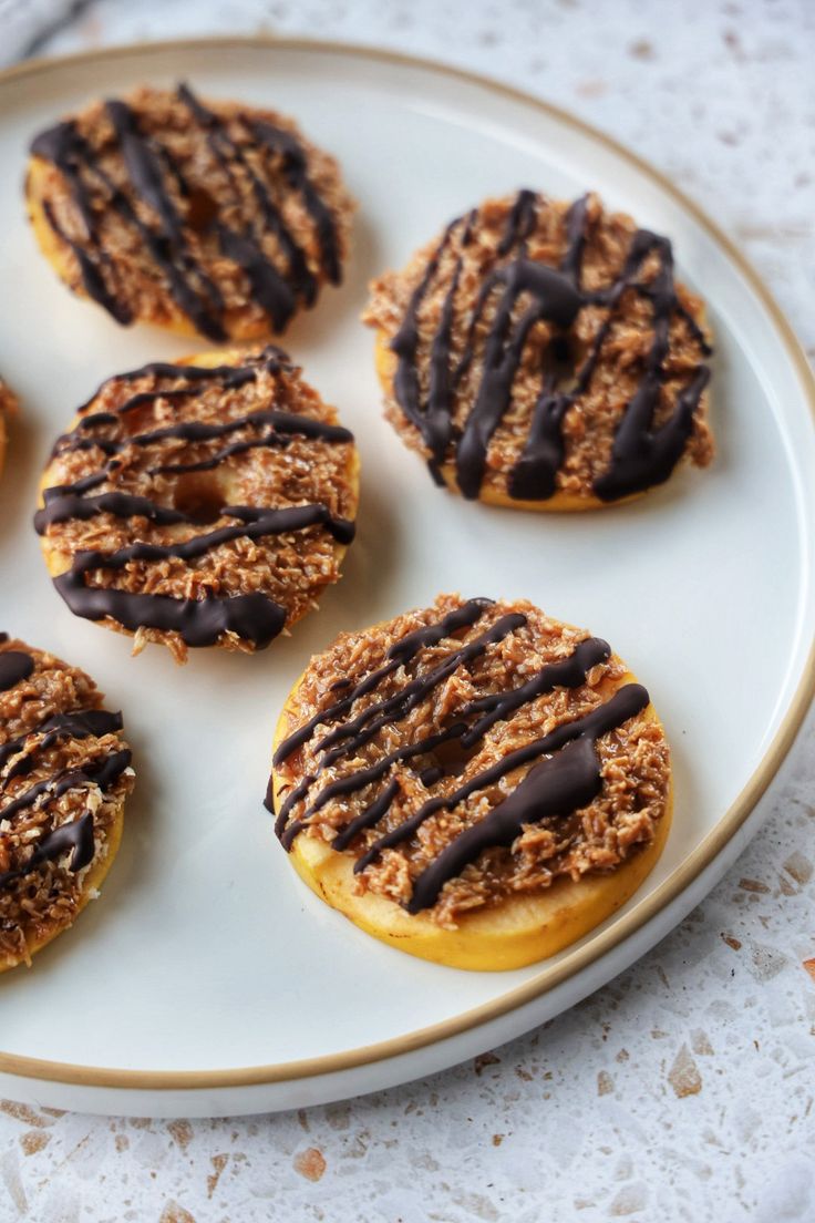 six donuts with chocolate and sprinkles on a plate