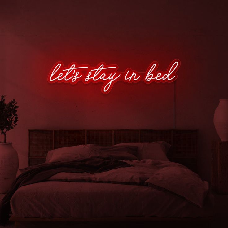 this is where the magic happens neon sign above a bed in a room with red lighting