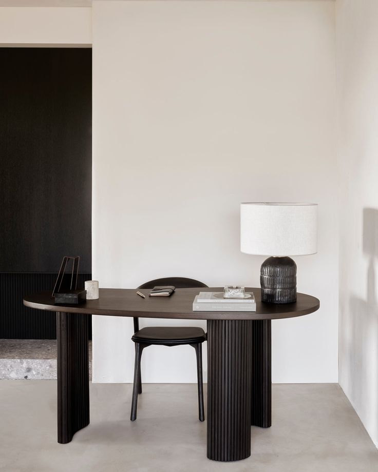 a table and chair in a room with a lamp on the wall next to it