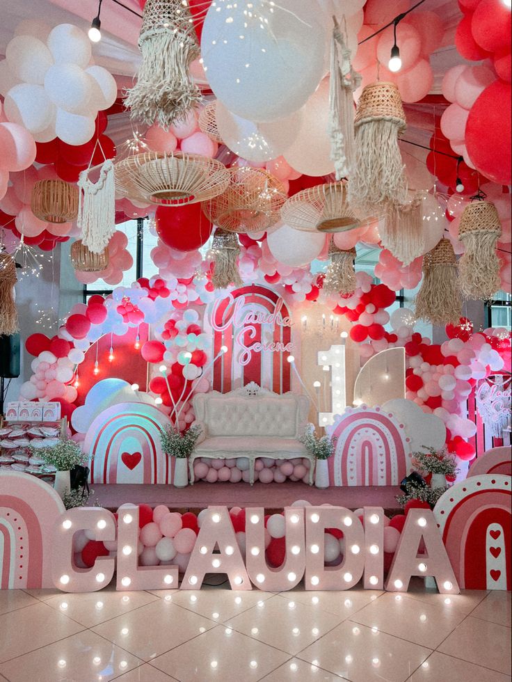 a room filled with lots of pink and white balloons hanging from the ceiling above it