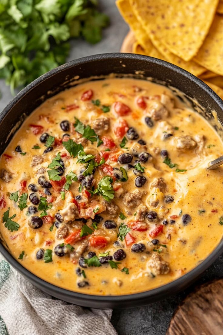 a black bowl filled with tortilla soup next to some tortilla chips