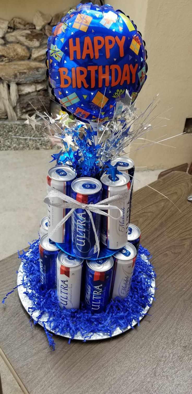 a birthday cake made out of soda cans and blue tinsels with the words happy birthday on it