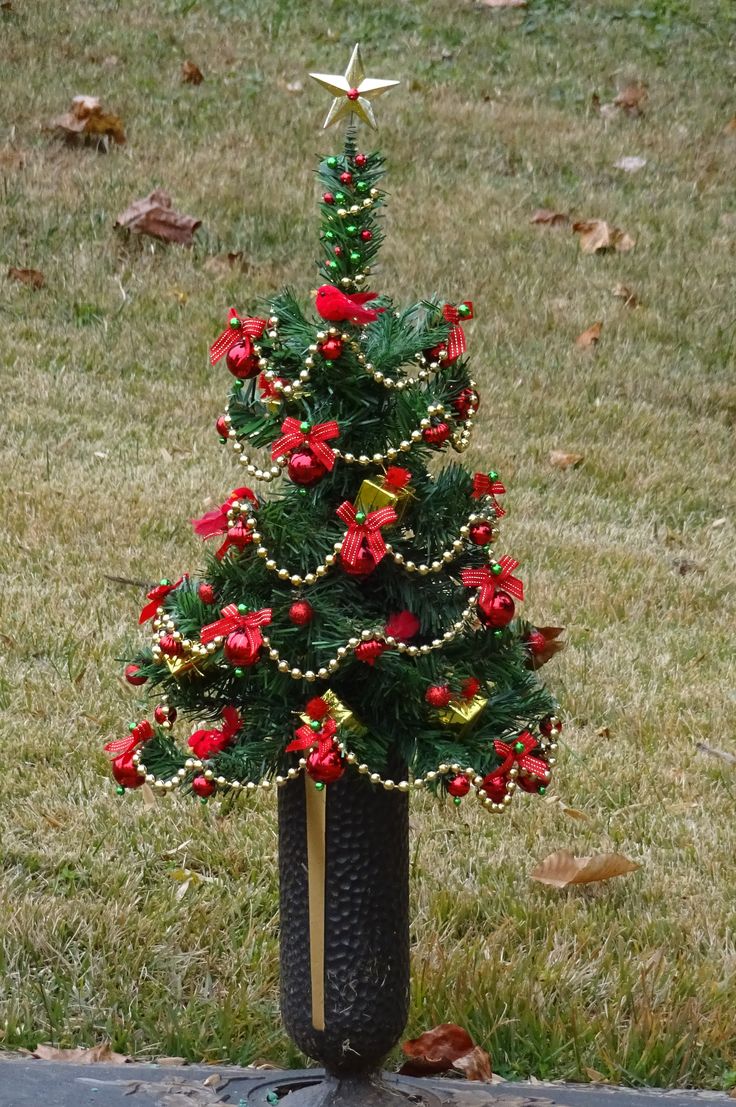 a small christmas tree in a vase on the ground