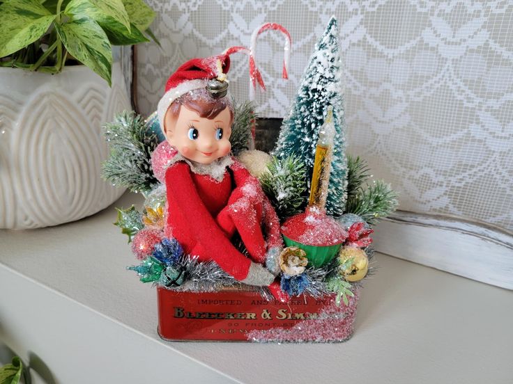 an elf figurine sitting on top of a shelf next to a christmas tree