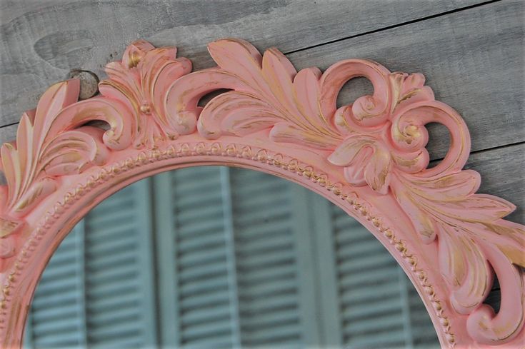 a pink mirror sitting on top of a wooden wall