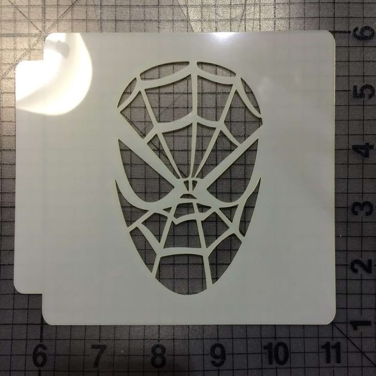 a cutout of a spiderman's face on a cutting mat