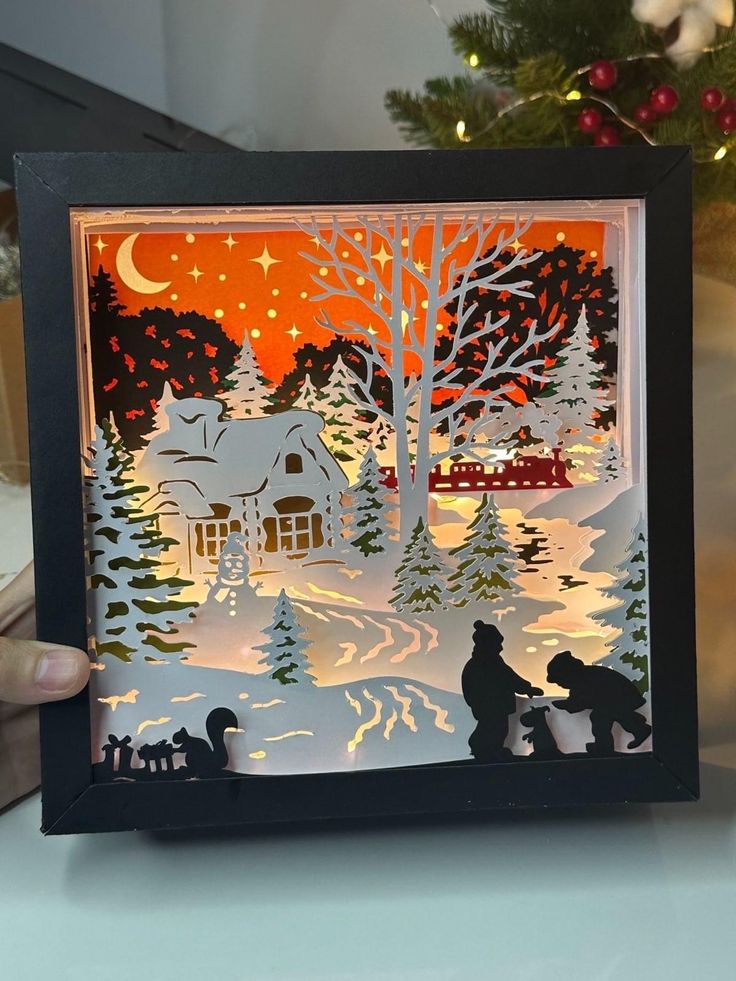 someone is holding up a paper cut christmas scene