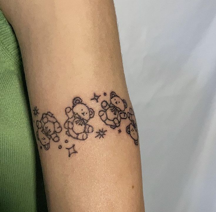 a woman with a tattoo on her arm that has teddy bears and stars all over it