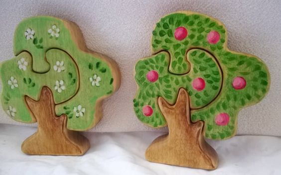 two wooden trees with pink and green leaves on them are sitting next to each other