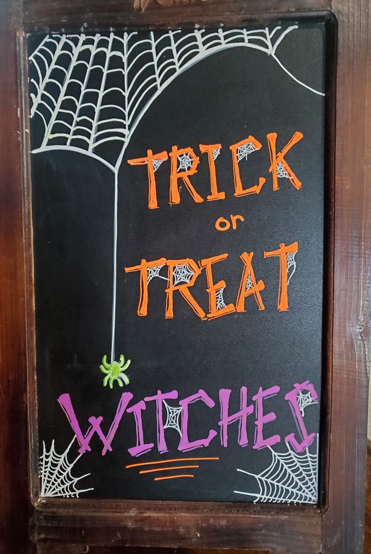 a chalkboard sign that says trick or treat, witches and webs on it