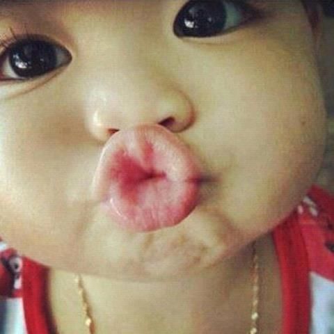 a close up of a baby making a funny face with its tongue sticking out to the side