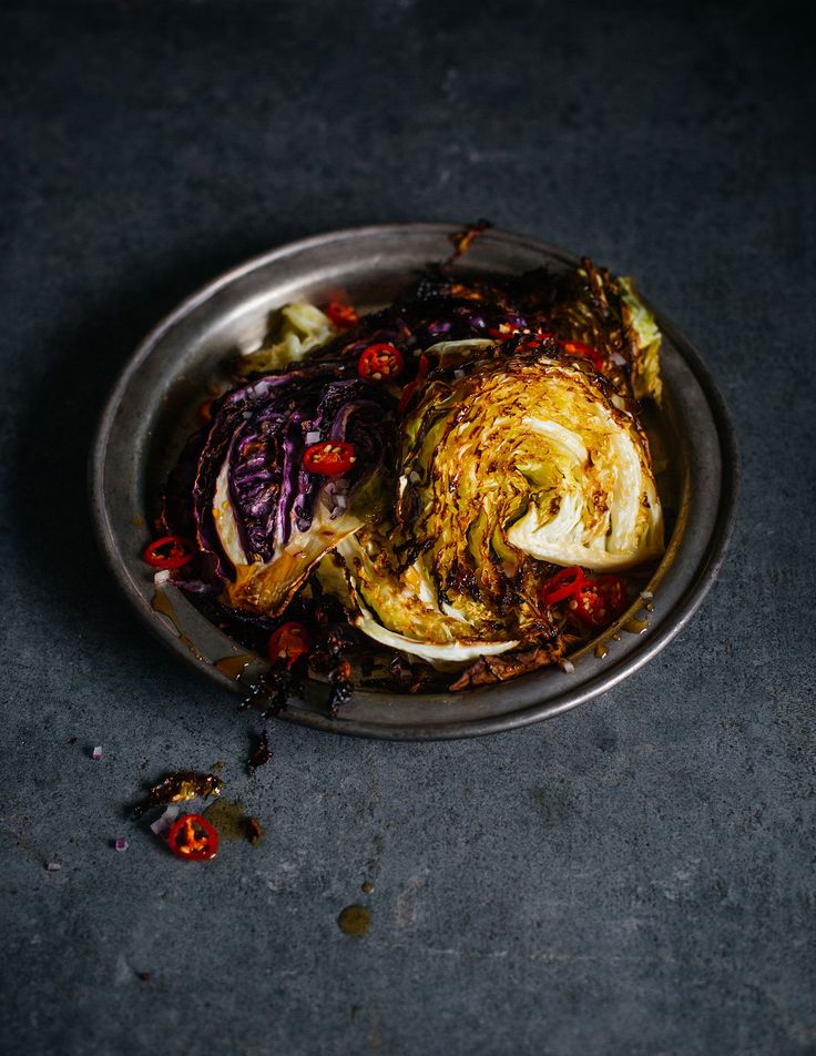 a metal bowl filled with vegetables on top of a black countertop next to a knife and fork