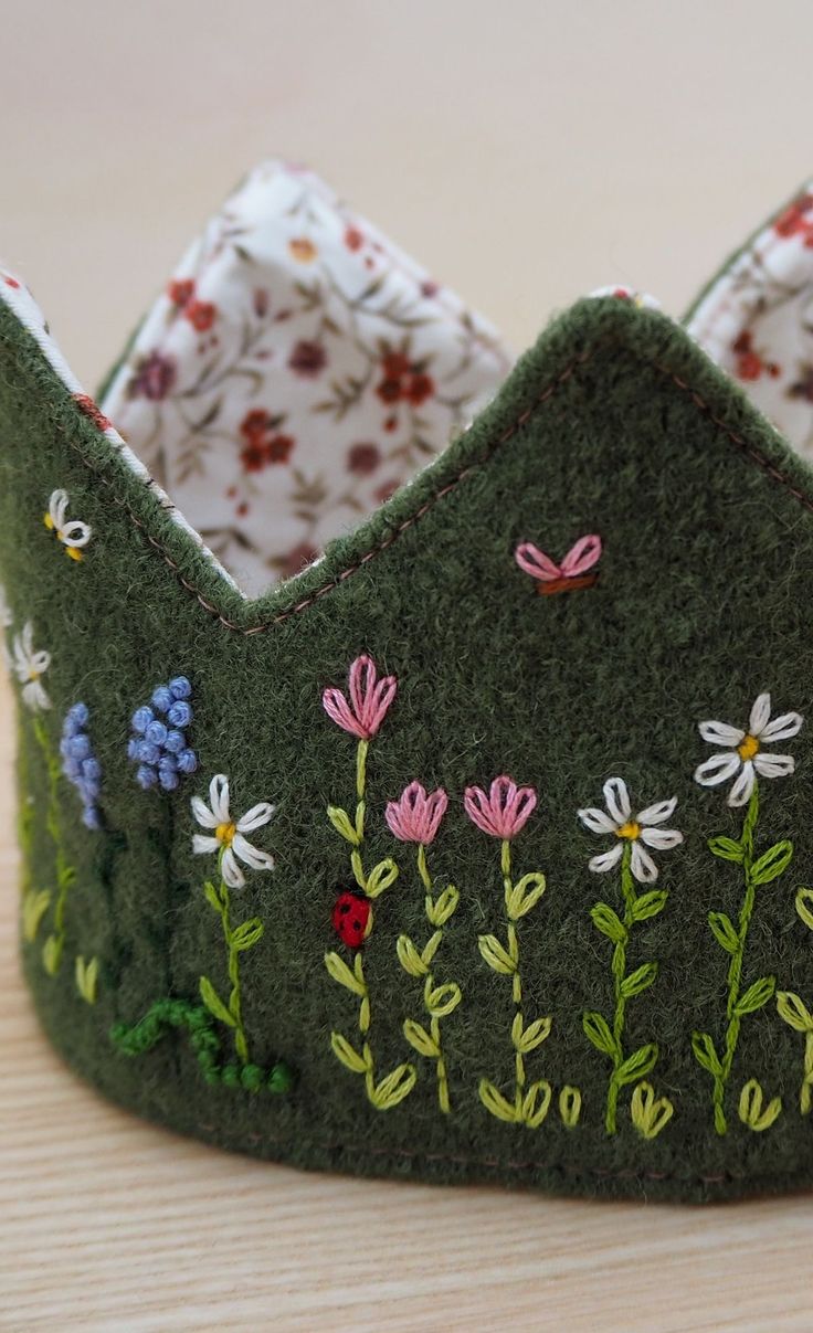 a green felt crown with flowers and butterflies on it