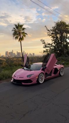 a pink sports car is parked on the side of the road with its doors open