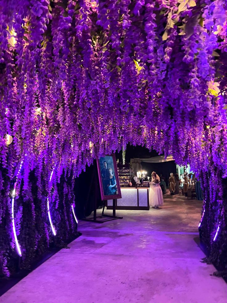 a bride and groom are standing under purple wistery trees at the end of a walkway