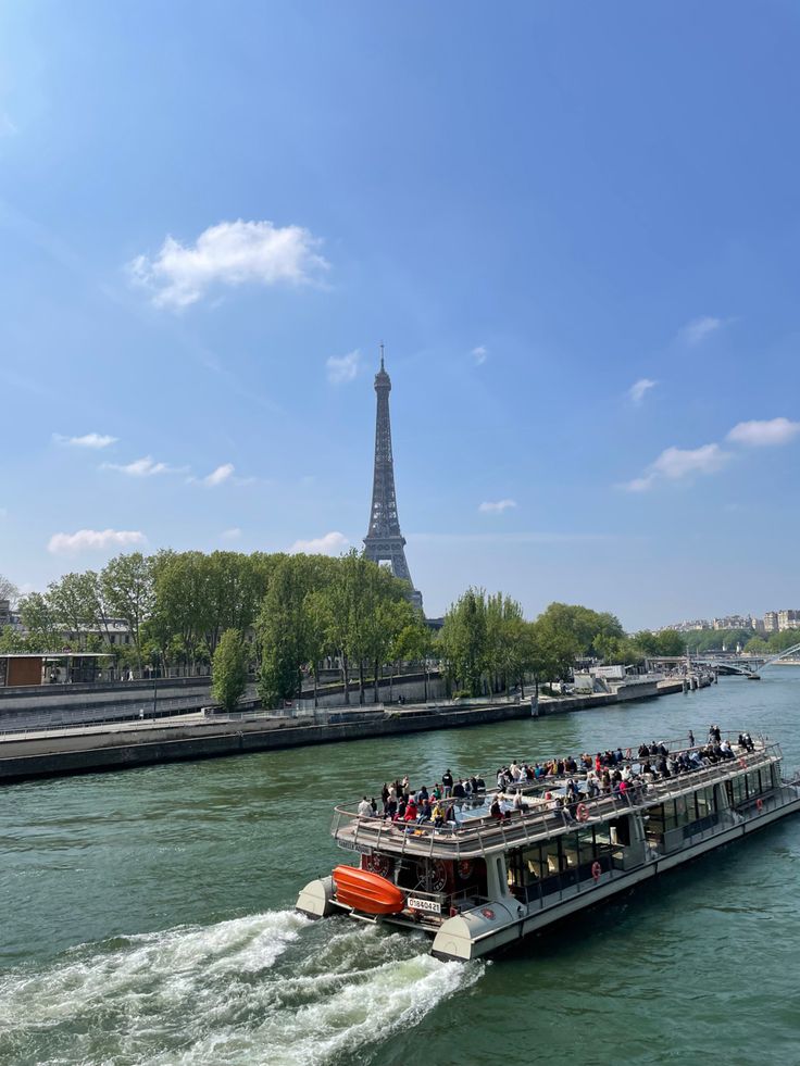 a boat full of people traveling down the river in front of the eiffel tower