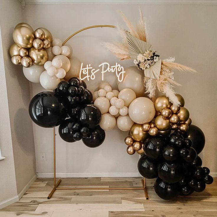 black and gold balloons are arranged in the shape of a arch