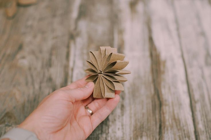 a hand holding a piece of brown paper with a flower on it's end