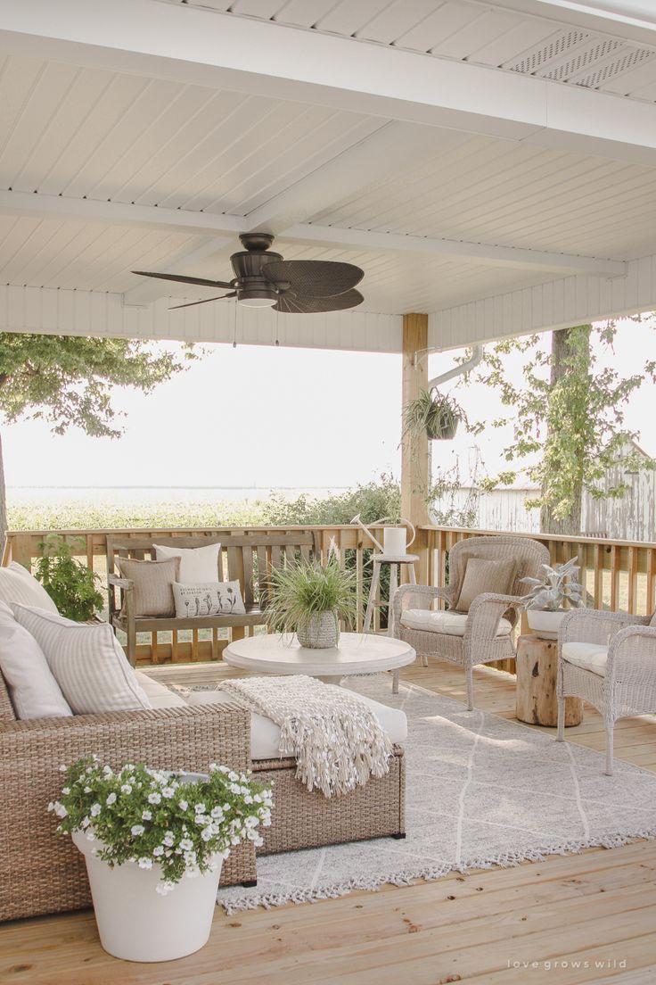 a porch with wicker furniture and a ceiling fan on top of the wooden deck