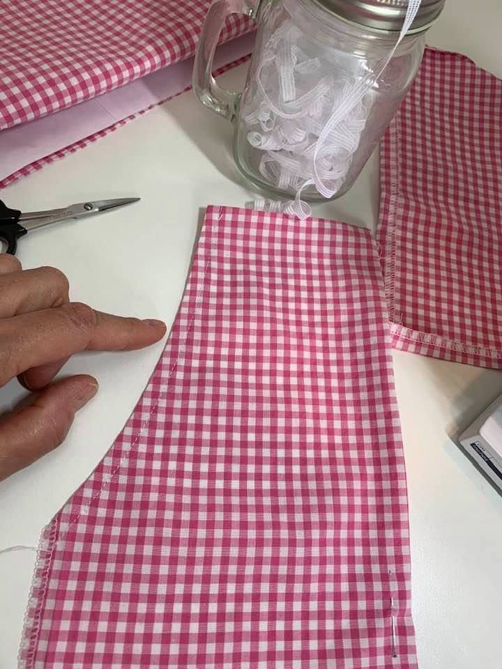 a person cutting fabric with scissors on a table next to a mason jar and other items