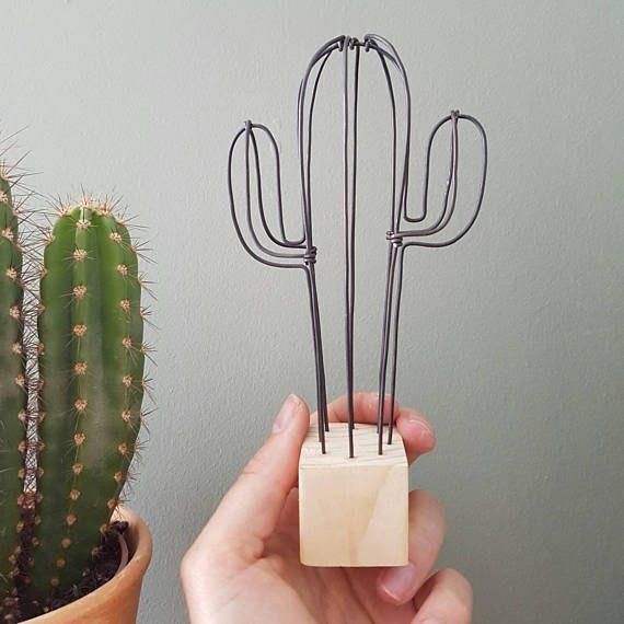 a person holding up a small cactus plant with metal forks in it's hands