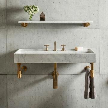 a bathroom sink with two gold faucets on the wall