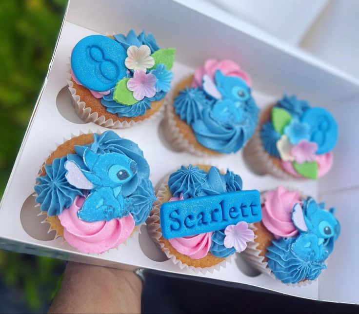 a person holding a box filled with cupcakes that say scrifet