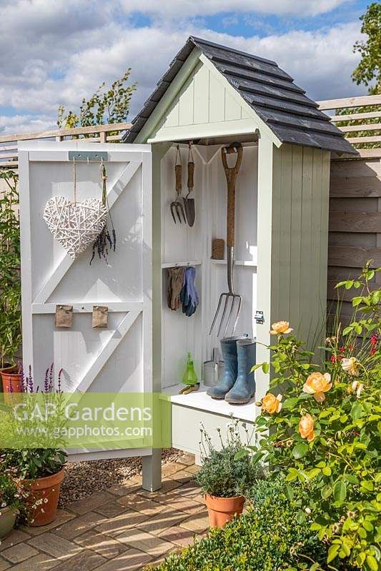 a garden shed with gardening tools hanging on the door