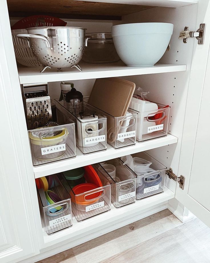 an organized pantry with clear bins and plastic containers on the bottom shelve