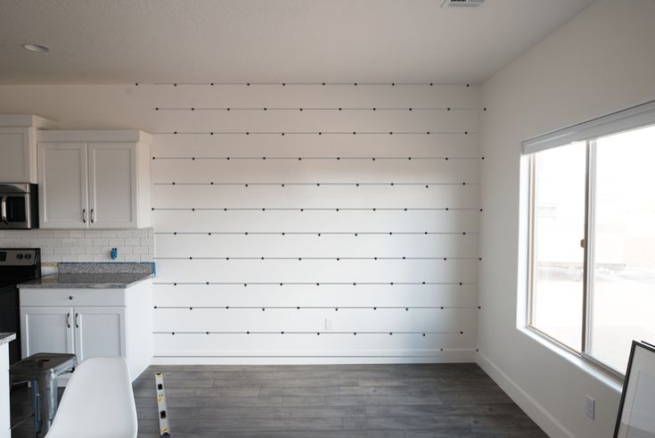 an empty kitchen with white cabinets and wood flooring