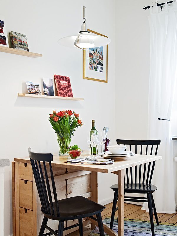 a small dining table with two chairs and a vase of flowers on the top shelf