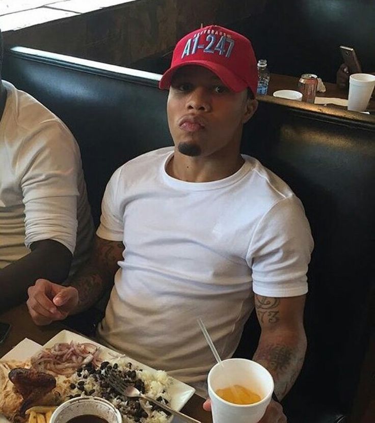 two men sitting at a table with food in front of them and drinks on the side