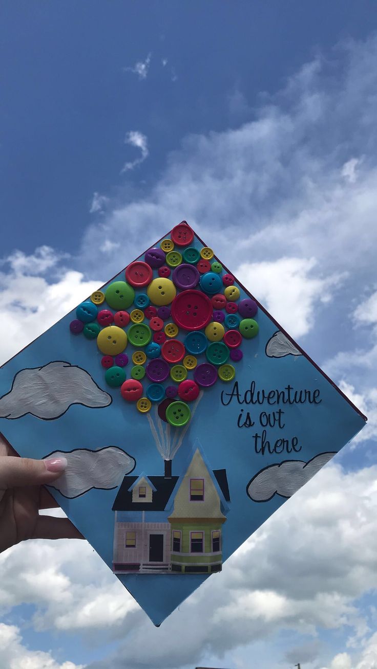 someone is holding up a graduation cap that has buttons on it and the words, adventure is out there