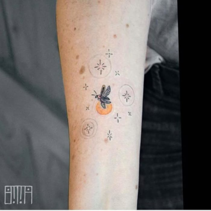 a woman's arm with tattoos on it, and an orange in the middle