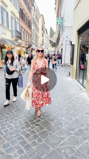 a woman in a red dress is walking down the street