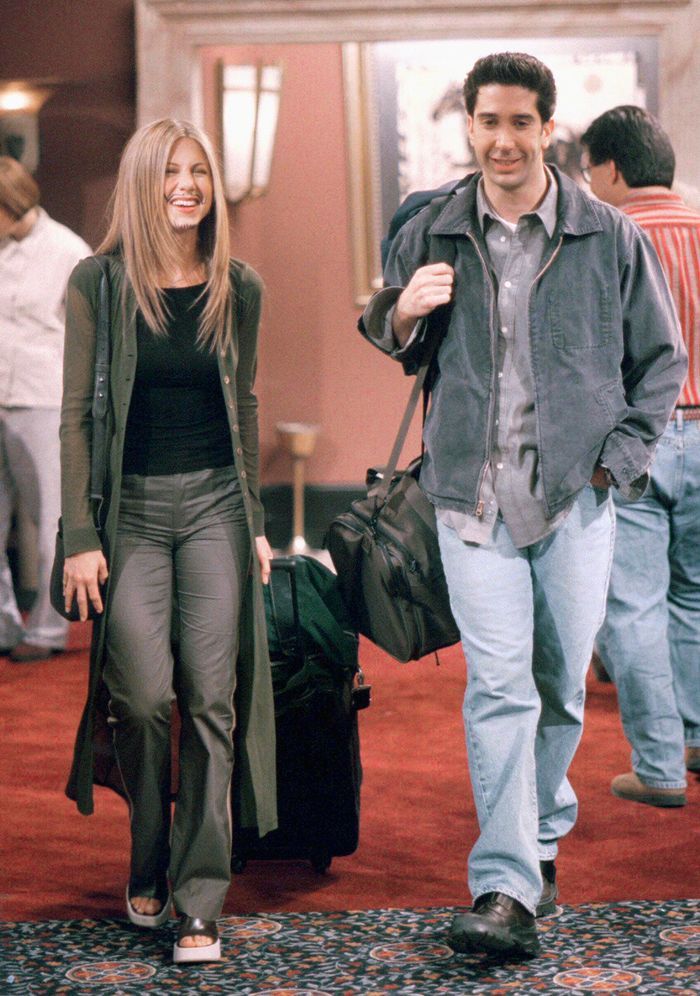 a man and woman are walking down the carpeted hallway with suitcases in hand