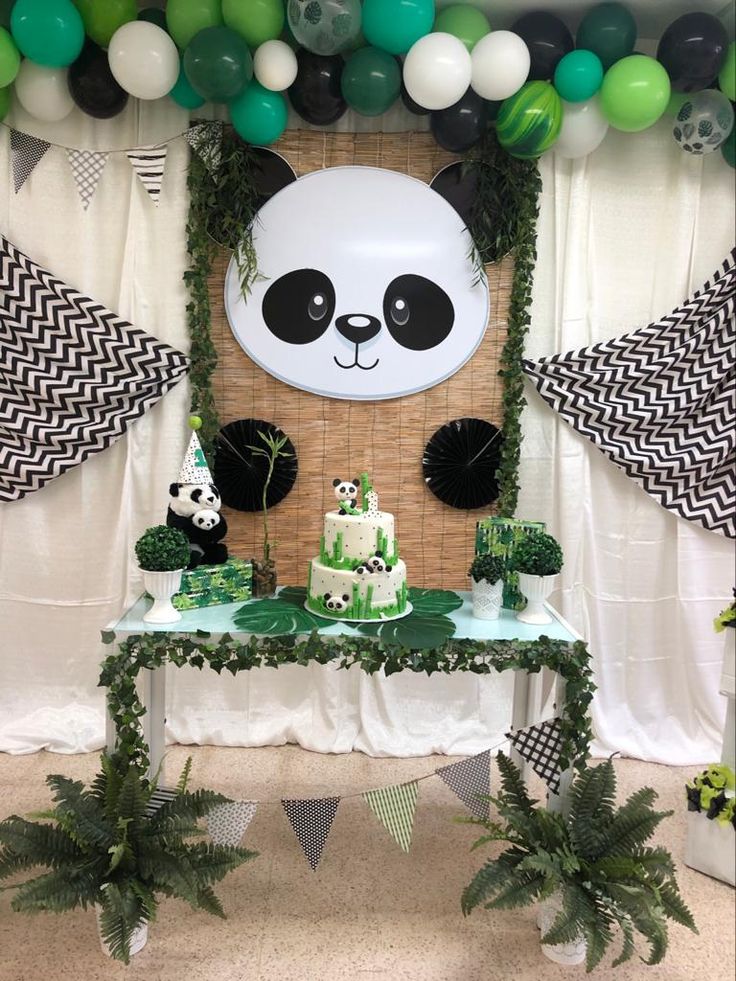 a panda bear themed birthday party with balloons and decorations on the wall, including cake