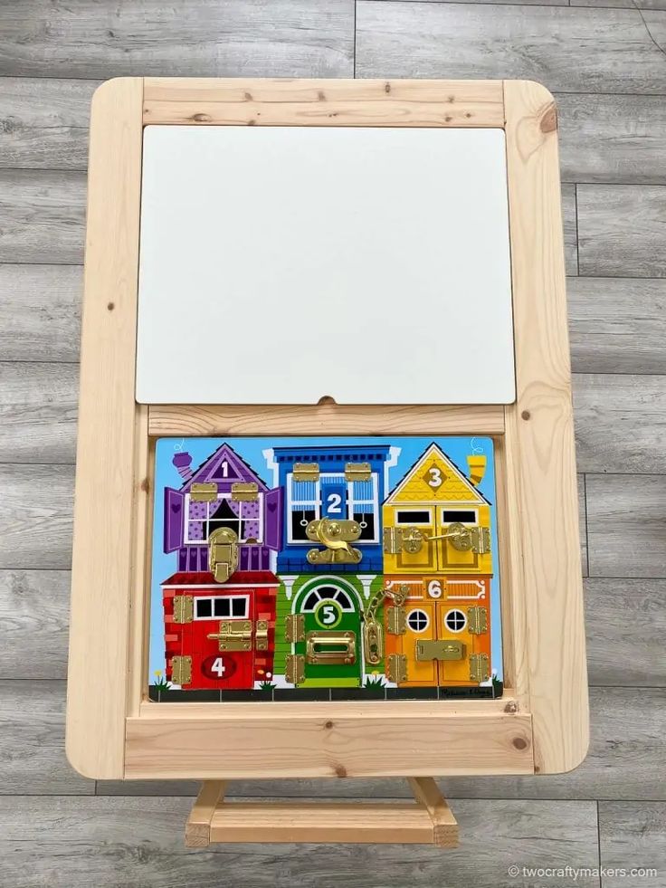 a wooden easel with an image of houses painted on the front and back side