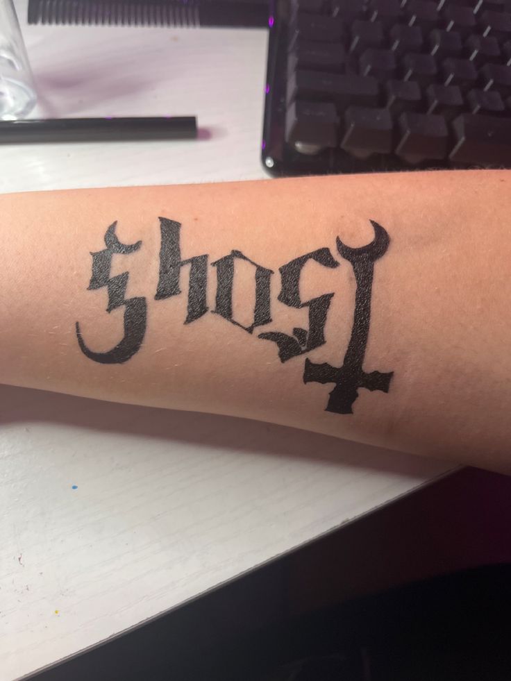 a person with a tattoo on their arm has the word jesus written in cursive writing