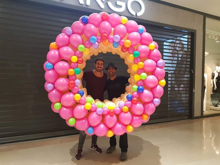 two men standing in front of a giant balloon wreath