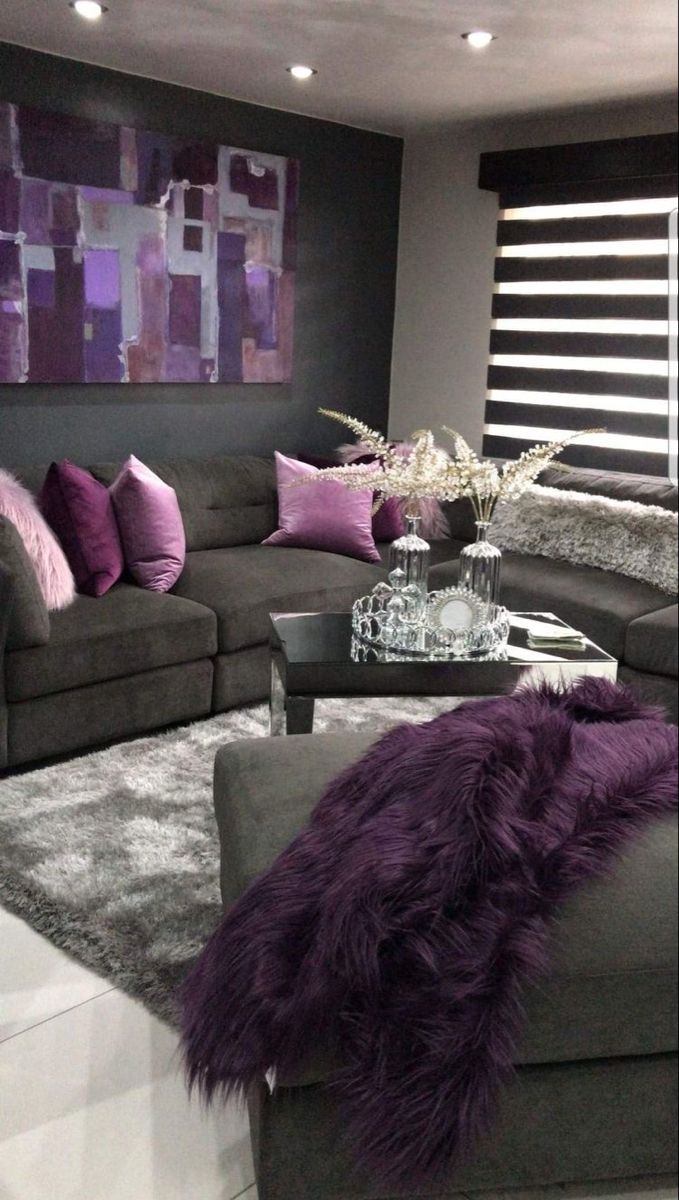 a living room filled with gray couches and purple pillows